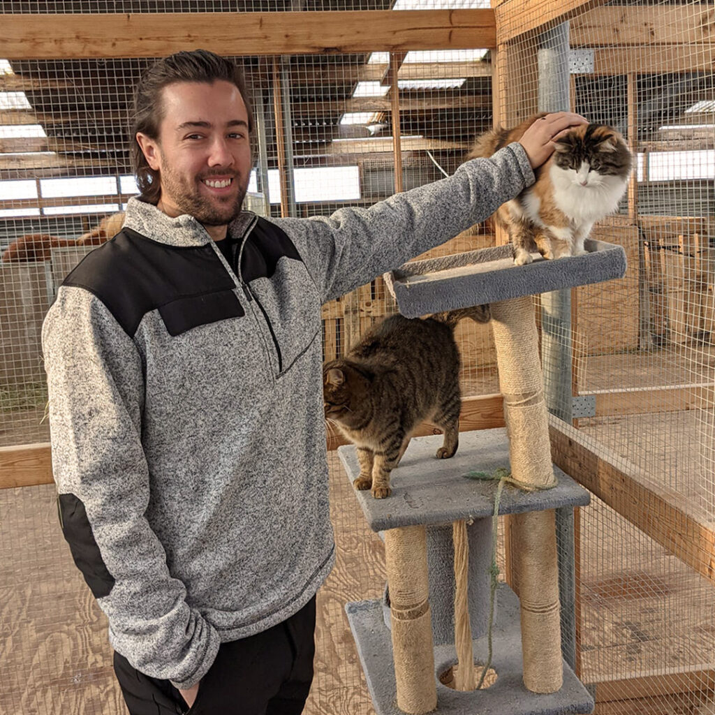 John visiting cats in an indoor enclosure