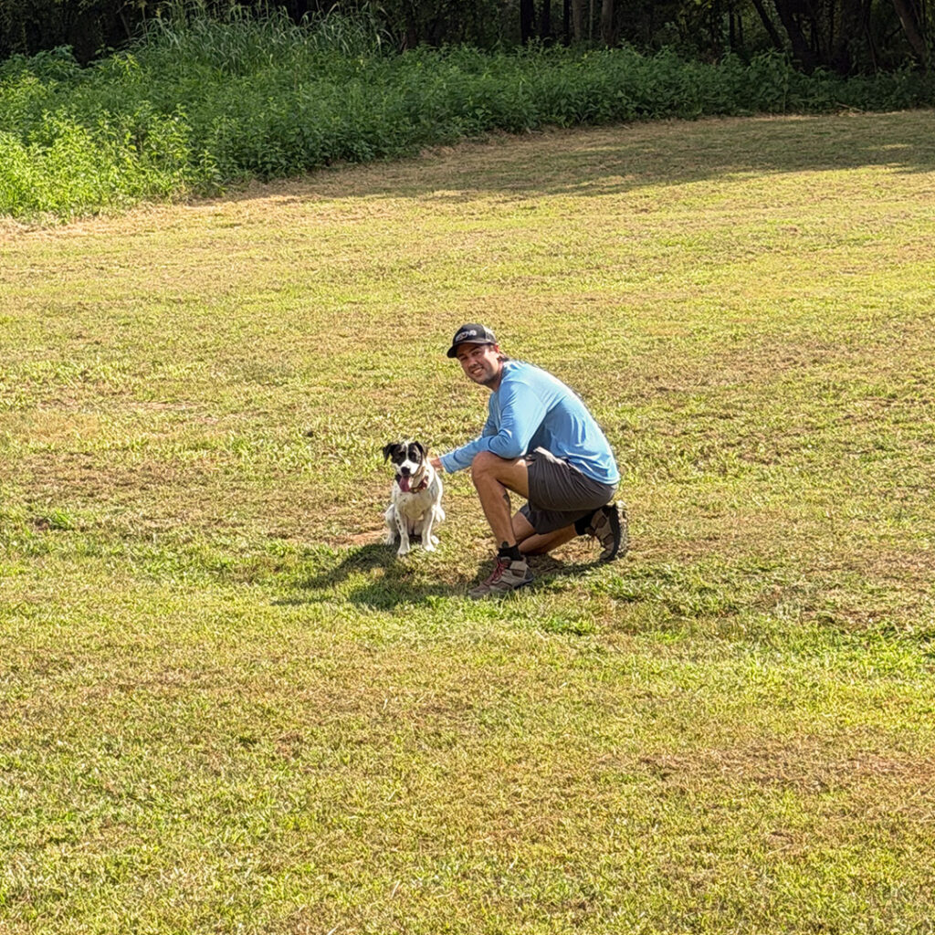 John working with a dog in the outdoor training field at Peanut's Pet Care